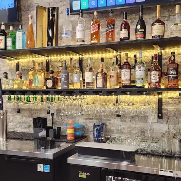 A well-stocked bar at Los Amigos, featuring various liquor bottles, glassware, and bar equipment.