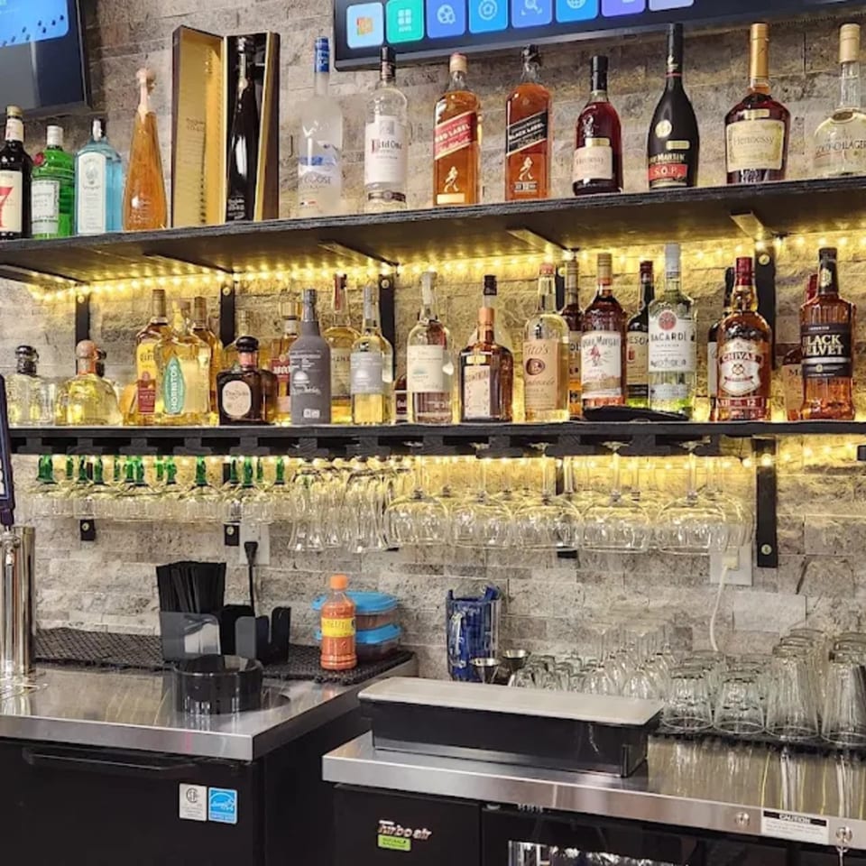 A well-stocked bar at Los Amigos, featuring various liquor bottles, glassware, and bar equipment.