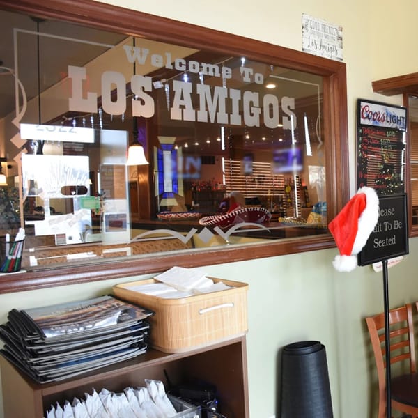 The entrance to Los Amigos restaurant, with a "Welcome To Los Amigos" sign on the glass.