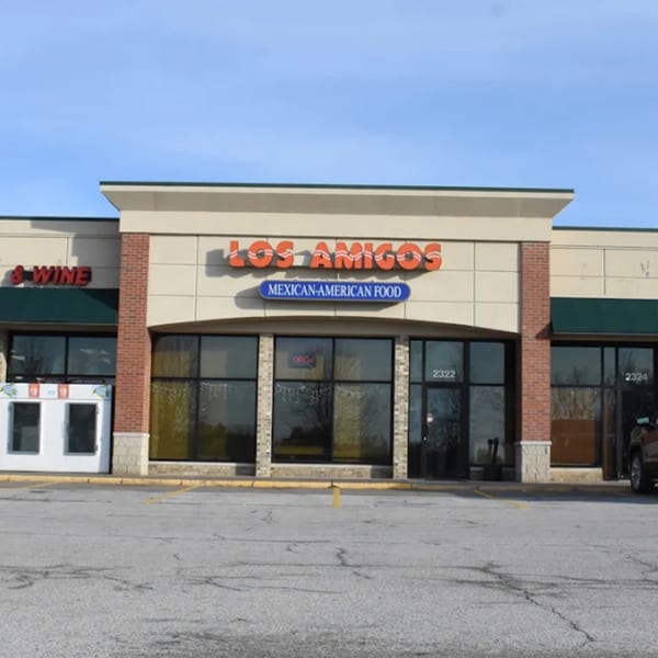 Exterior of Los Amigos Mexican-American Food restaurant with a parking lot in the foreground.