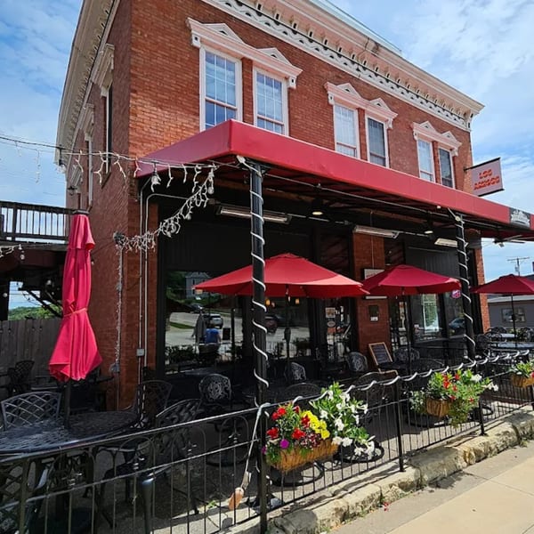 Los Amigos Mexican restaurant's outdoor patio with red umbrellas, black tables, and flower boxes.