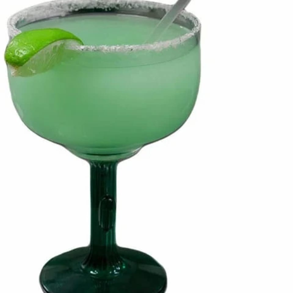 Green margarita in a stemmed glass with a salted rim, lime wedge, and straw.