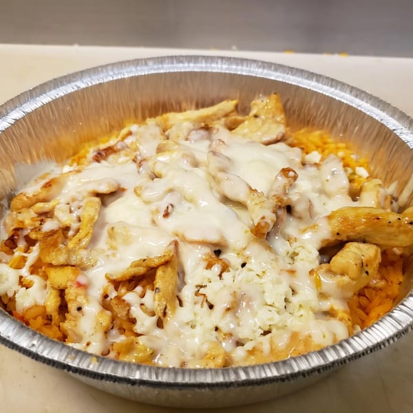 Los Amigos' chicken and rice dish, topped with white cheese sauce, in a foil takeout container.
